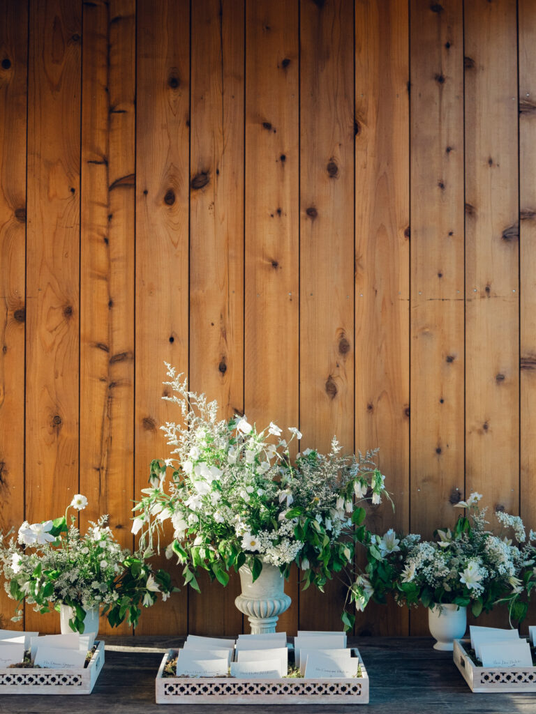 Rehearsal dinner on hilltop of Tennessee countryside resort Southall Farm & Inn. Classic whimsical white florals decorate this dinner reception with timeless garden-inspired floral design. Escort cards for wedding reception styled in moss trays. Destination wedding outside Nashville, TN. Design by Rosemary & Finch Floral Design in Nashville, TN. 