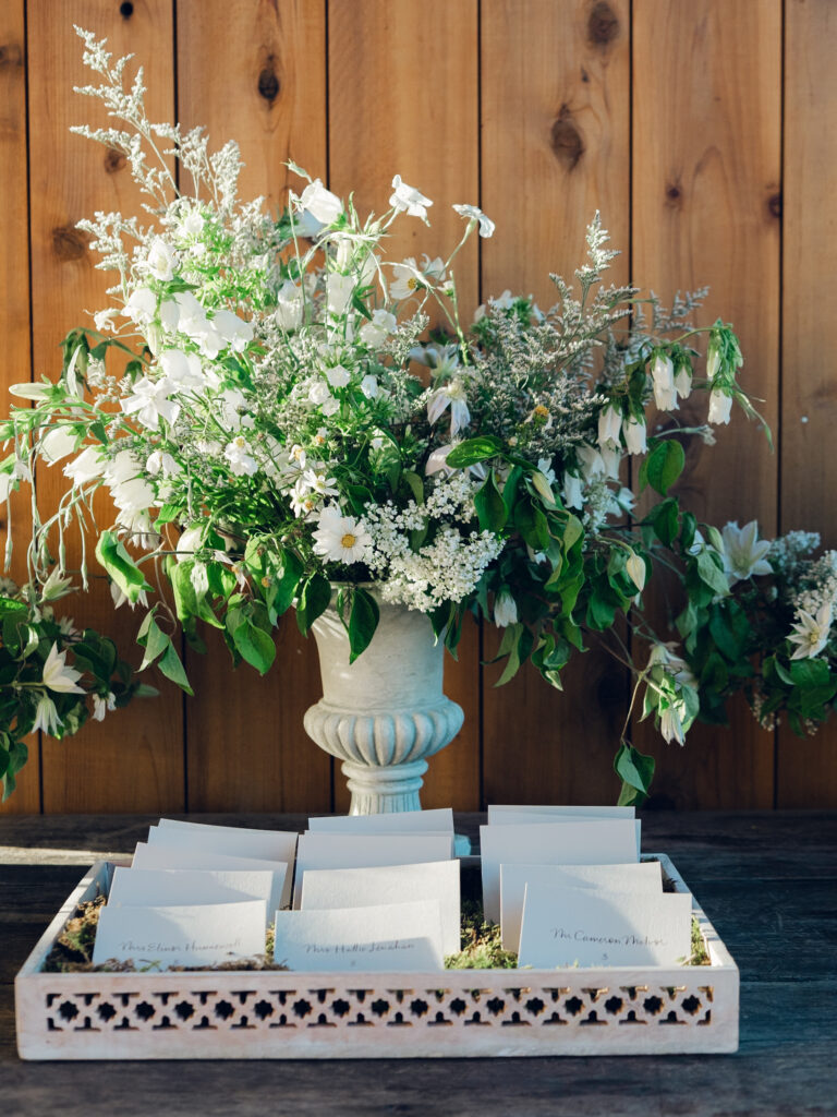 Rehearsal dinner on hilltop of Tennessee countryside resort Southall Farm & Inn. Classic whimsical white florals decorate this dinner reception with timeless garden-inspired floral design. Escort cards for wedding reception styled in moss trays. Destination wedding outside Nashville, TN. Design by Rosemary & Finch Floral Design in Nashville, TN. 