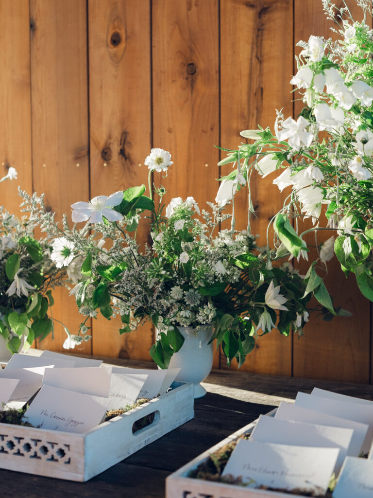 Rehearsal dinner on hilltop of Tennessee countryside resort Southall Farm & Inn. Classic whimsical white florals decorate this dinner reception with timeless garden-inspired floral design. Escort cards for wedding reception styled in moss trays. Destination wedding outside Nashville, TN. Design by Rosemary & Finch Floral Design in Nashville, TN. 