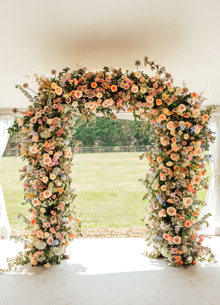 Summer wedding ceremony arch in pastel colors. Wedding ceremony floral arch with pastel purple, soft pink, and baby blue. Colorful florals for summer wedding ceremony in Nashville, TN. Design by Rosemary & Finch Floral Design in Nashville, TN.