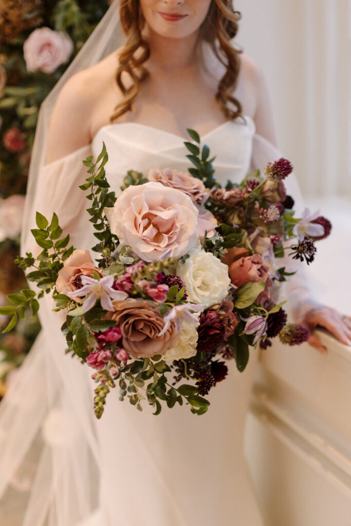 Lush bridal bouquet with floral colors in mauve, plum, eggplant, and cream. Bridal bouquet with texture and airy details. Fall wedding bouquets in muted colors. Bridesmaid’s bouquets consisting of roses, wildflowers, berries, and greenery. Design by Rosemary & Finch Floral Design in Nashville, TN. 