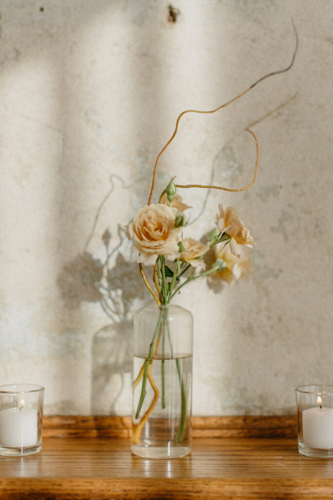 Minimalist floral design with single stem bud vases creates artful and whimsical design for fall wedding reception. Fall wedding floral design in tones of yellow, cream, and toffee. Unique and whimsical floral design. Dainty blooms of tulips, spray roses, and ranunculus create colorful fall floral design. Urban fall wedding with modern romantic details. Design by Rosemary & Finch Floral Design in Nashville, TN.