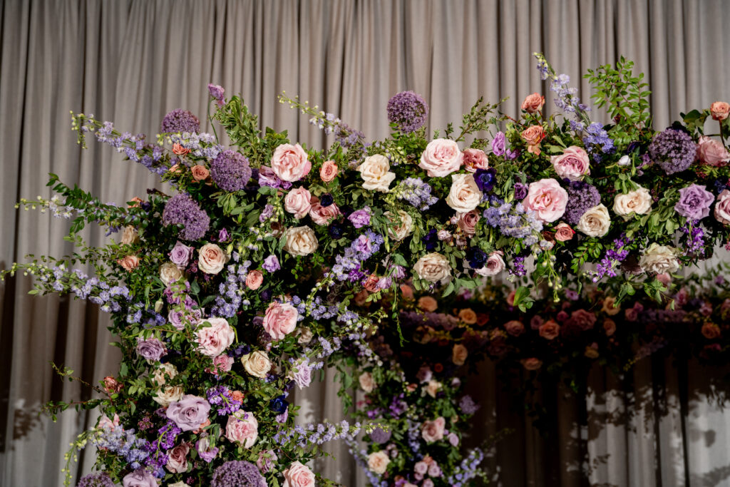 Lush floral chuppah in hues of lavender, plush, plum, and cream for fall wedding ceremony. Aisle adorned with floral ground meadows at the base of each chair. Wildflowers, roses, and growing greenery for fall wedding florals. Unique purple wedding colors for fall wedding ceremony. Design by Rosemary & Finch Floral Design in Nashville, TN. 