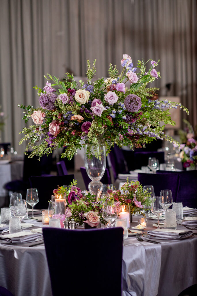 Lush florals for elevated centerpieces for fall wedding reception tables. Lavender and purple color scheme for fall wedding at the Four Seasons Hotel. Floral colors in lavender, blush, mauve, and rose. Unique and fun candles in purple tones decorate dinner tables. Design by Rosemary & Finch Floral Design in Nashville, TN. 