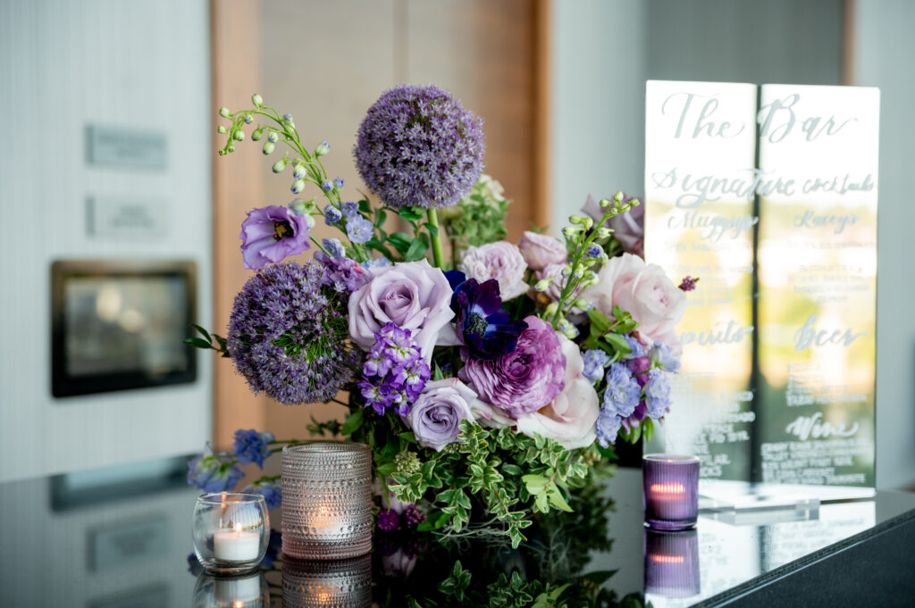 Elegant cocktail hour florals decorate the bar and cocktail tables of this fall wedding reception. Purple wedding flowers in hues of lavender, mauve, blush, and plum. Fall wildflowers for fall wedding reception. Design by Rosemary & Finch Floral Design in Nashville, TN. 