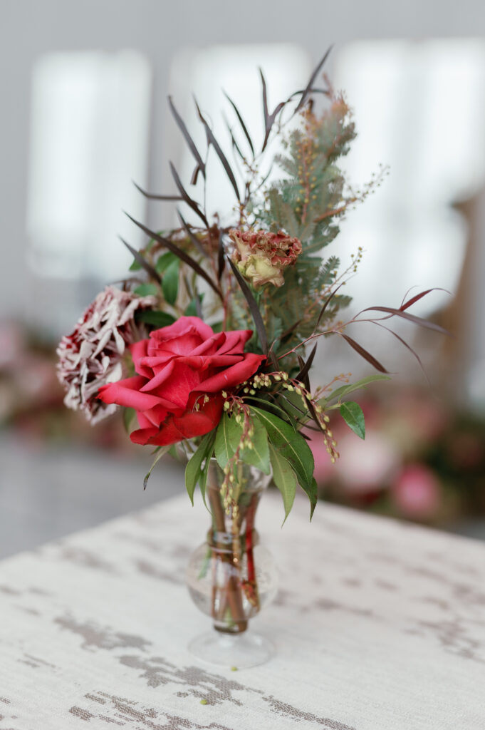 Cocktail hour florals for winter wedding. Moody jewel tone wedding reception florals in ruby, blush, plum, and magenta. Bar menu floral meadows for wedding reception bar. Escort Display mirrors with floral meadows. Unique floral touches in cocktail reception of winter wedding in downtown Nashville. Design by Rosemary & Finch Floral Design.