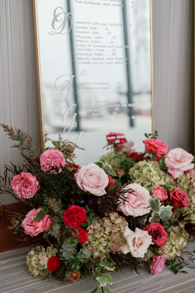 Cocktail hour florals for winter wedding. Moody jewel tone wedding reception florals in ruby, blush, plum, and magenta. Bar menu floral meadows for wedding reception bar. Escort Display mirrors with floral meadows. Unique floral touches in cocktail reception of winter wedding in downtown Nashville. Design by Rosemary & Finch Floral Design.