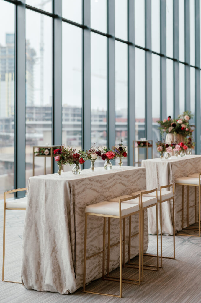 Cocktail hour florals for winter wedding. Moody jewel tone wedding reception florals in ruby, blush, plum, and magenta. Bar menu floral meadows for wedding reception bar. Escort Display mirrors with floral meadows. Unique floral touches in cocktail reception of winter wedding in downtown Nashville. Design by Rosemary & Finch Floral Design.