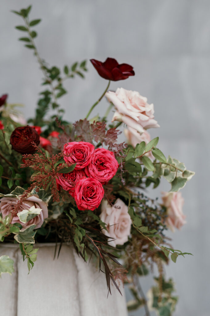 Cocktail hour florals for winter wedding. Moody jewel tone wedding reception florals in ruby, blush, plum, and magenta. Bar menu floral meadows for wedding reception bar. Escort Display mirrors with floral meadows. Unique floral touches in cocktail reception of winter wedding in downtown Nashville. Design by Rosemary & Finch Floral Design.