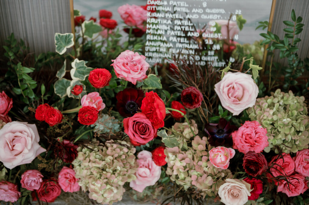 Cocktail hour florals for winter wedding. Moody jewel tone wedding reception florals in ruby, blush, plum, and magenta. Bar menu floral meadows for wedding reception bar. Escort Display mirrors with floral meadows. Unique floral touches in cocktail reception of winter wedding in downtown Nashville. Design by Rosemary & Finch Floral Design.