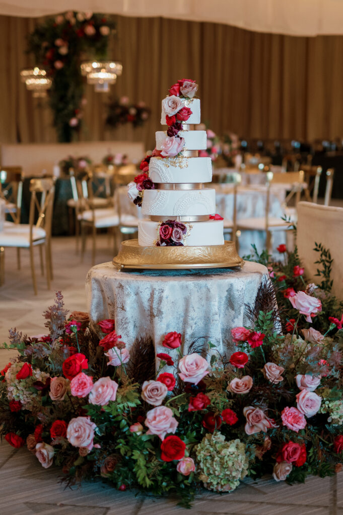 Lush cake table ground meadows. Moody jewel tone wedding reception florals in ruby, blush, plum, and magenta. Winter wedding reception at the Four Seasons. Winter wedding florals. Rose heavy wedding florals. Design by Rosemary & Finch Floral Design.