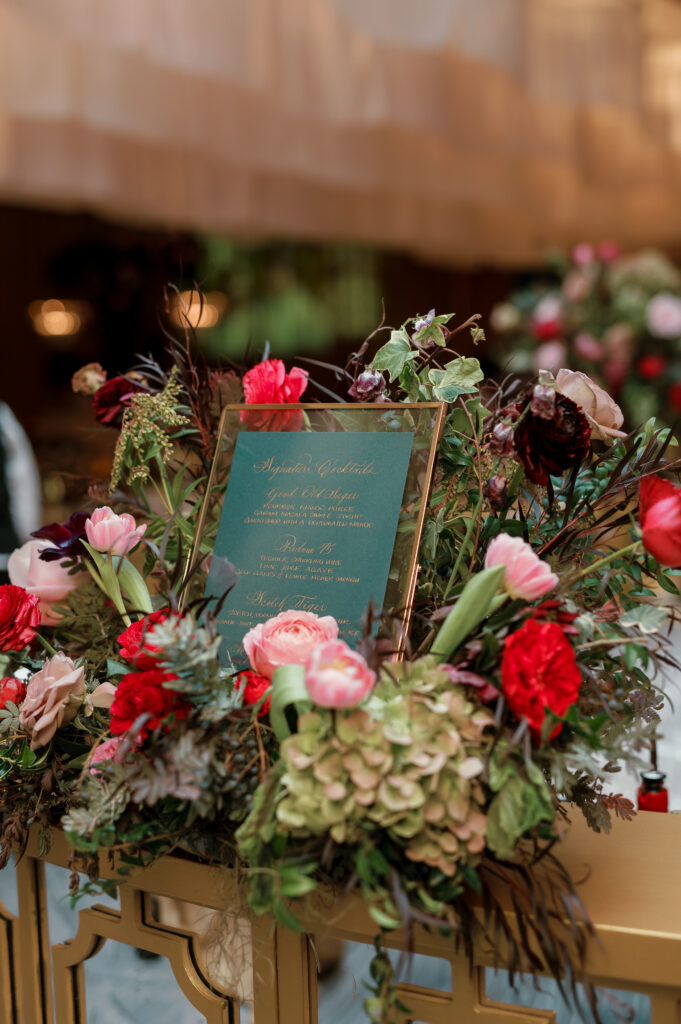 Unique bar menu floral design for wedding reception. Moody jewel tone wedding reception florals in ruby, blush, plum, and magenta. Unique wedding reception floral designs. Wedding reception in Downtown Nashville at the Four Seasons. Design by Rosemary & Finch Floral Design.