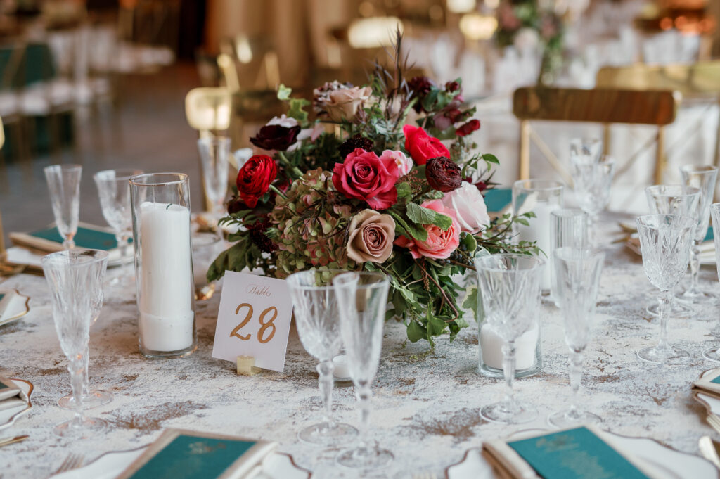 Floral forward low centerpieces for winter wedding. Jewel tone winter wedding color palette. Destination floral design in Nashville, TN. Winter floral colors in ruby, blush, plum, and magenta. Design by Rosemary & Finch Floral Design.