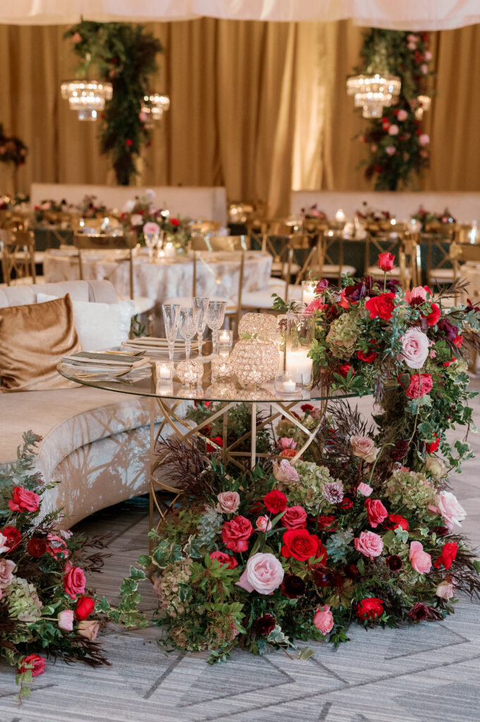 Sweetheart table surrounded by floral meadows in wedding reception. Moody jewel tone wedding reception florals in ruby, blush, plum, and magenta. Winter wedding reception at the Four Seasons. Lush floral moment for wedding sweetheart table. Design by Rosemary & Finch Floral Design. 