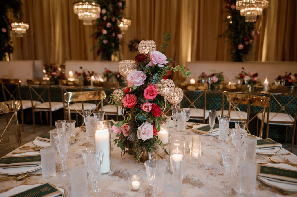 Candelabra with florals surrounding base on wedding tables. Lush florals on crystal candles in for winter wedding reception. Moody jewel tone wedding reception florals in ruby, blush, plum, and magenta. Unique wedding reception centerpieces. Wedding reception in Downtown Nashville at the Four Seasons. Design by Rosemary & Finch Floral Design.