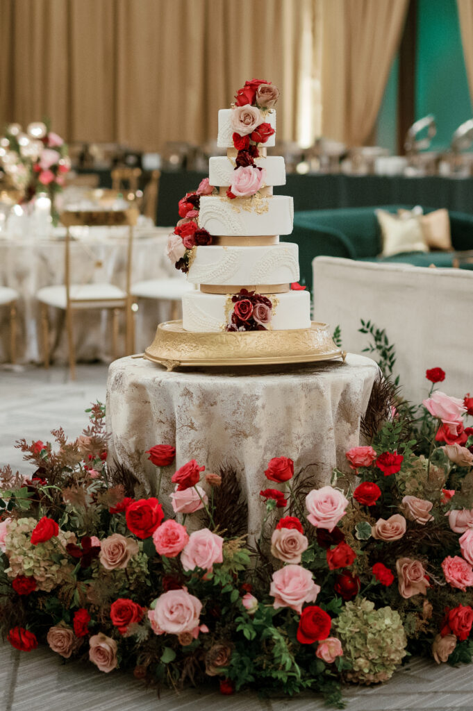 Lush cake table ground meadows. Moody jewel tone wedding reception florals in ruby, blush, plum, and magenta. Winter wedding reception at the Four Seasons. Winter wedding florals. Rose heavy wedding florals. Design by Rosemary & Finch Floral Design.