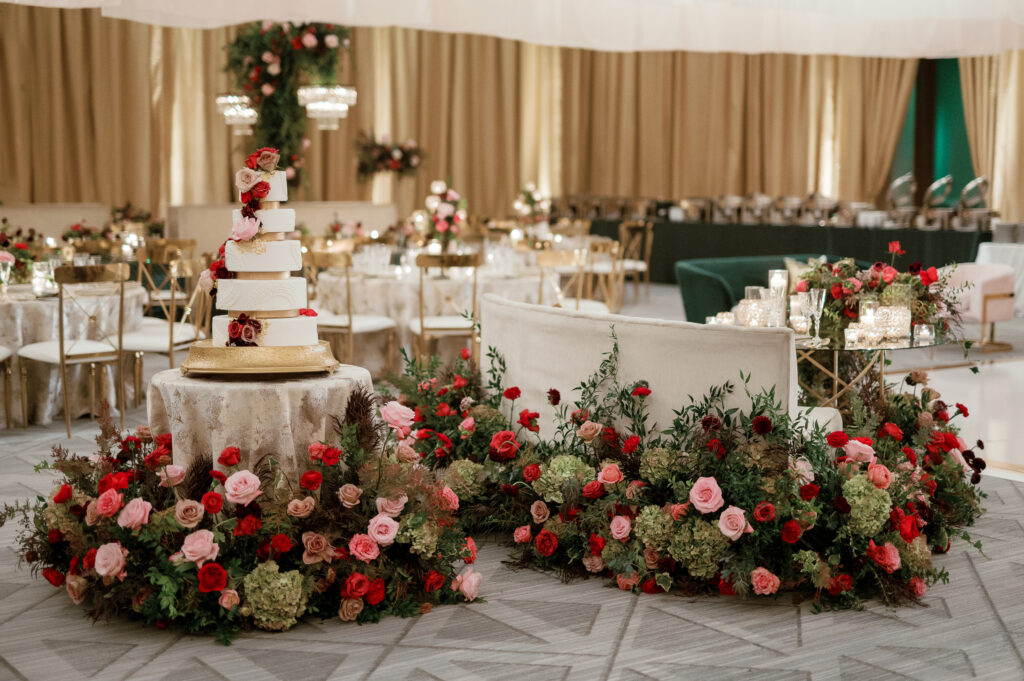 Sweetheart table surrounded by floral meadows in wedding reception. Moody jewel tone wedding reception florals in ruby, blush, plum, and magenta. Winter wedding reception at the Four Seasons. Lush floral moment for wedding sweetheart table. Design by Rosemary & Finch Floral Design. 