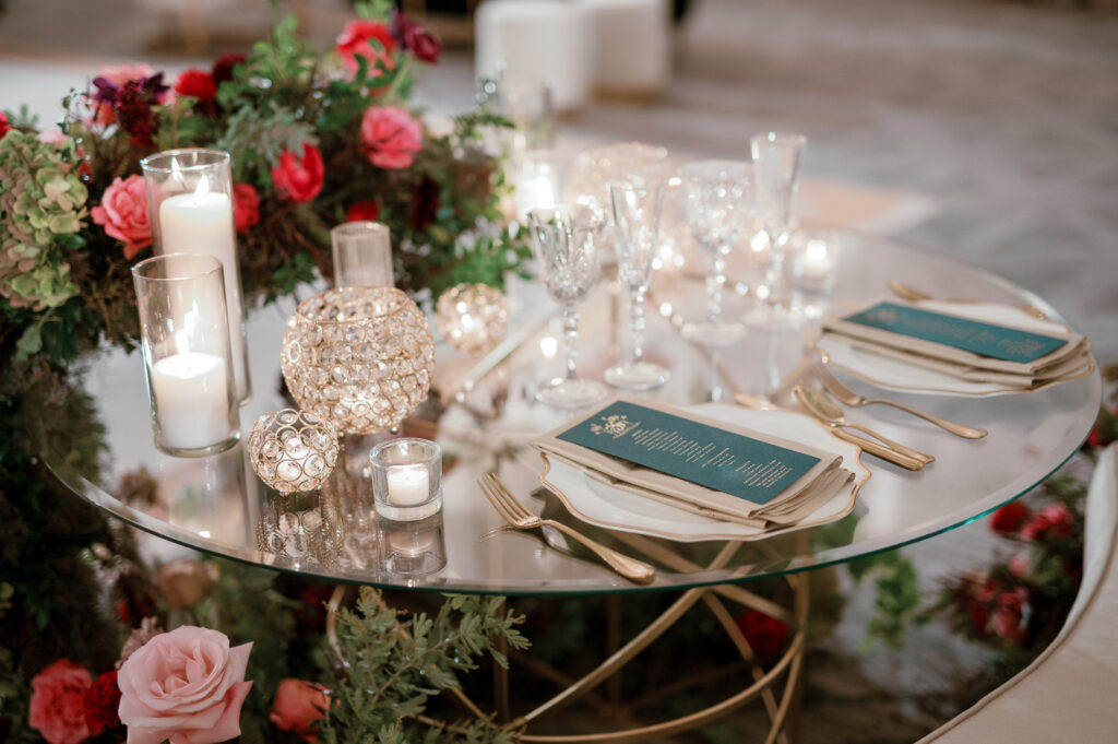 Sweetheart table surrounded by floral meadows in wedding reception. Moody jewel tone wedding reception florals in ruby, blush, plum, and magenta. Winter wedding reception at the Four Seasons. Lush floral moment for wedding sweetheart table. Design by Rosemary & Finch Floral Design. 