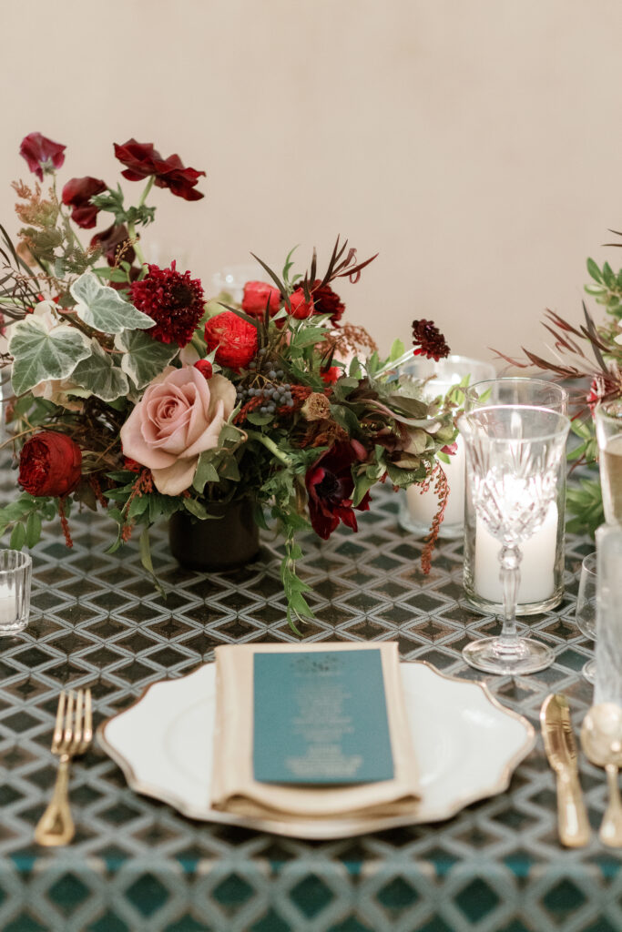 Jewel tone wedding reception florals with reception table floral cascades and table meadows. Winter floral colors in ruby, blush, plum, and magenta. Accent arrangement runners for wedding reception tablescapes. Design by Rosemary & Finch Floral Design.