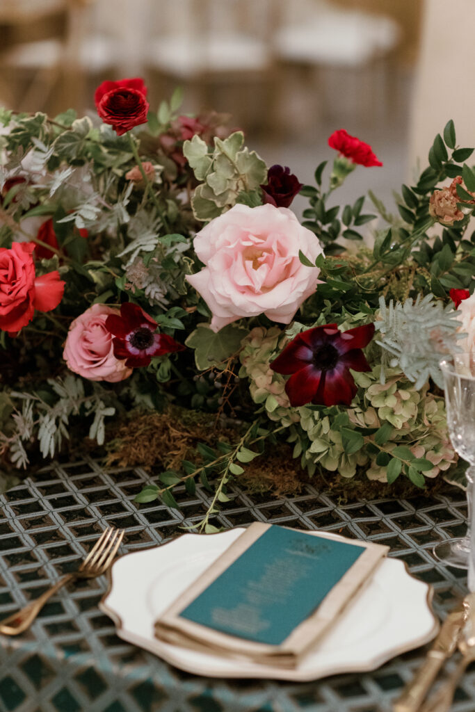 Jewel tone wedding reception florals with reception table floral cascades and table meadows. Winter floral colors in ruby, blush, plum, and magenta. Accent arrangement runners for wedding reception tablescapes. Design by Rosemary & Finch Floral Design.