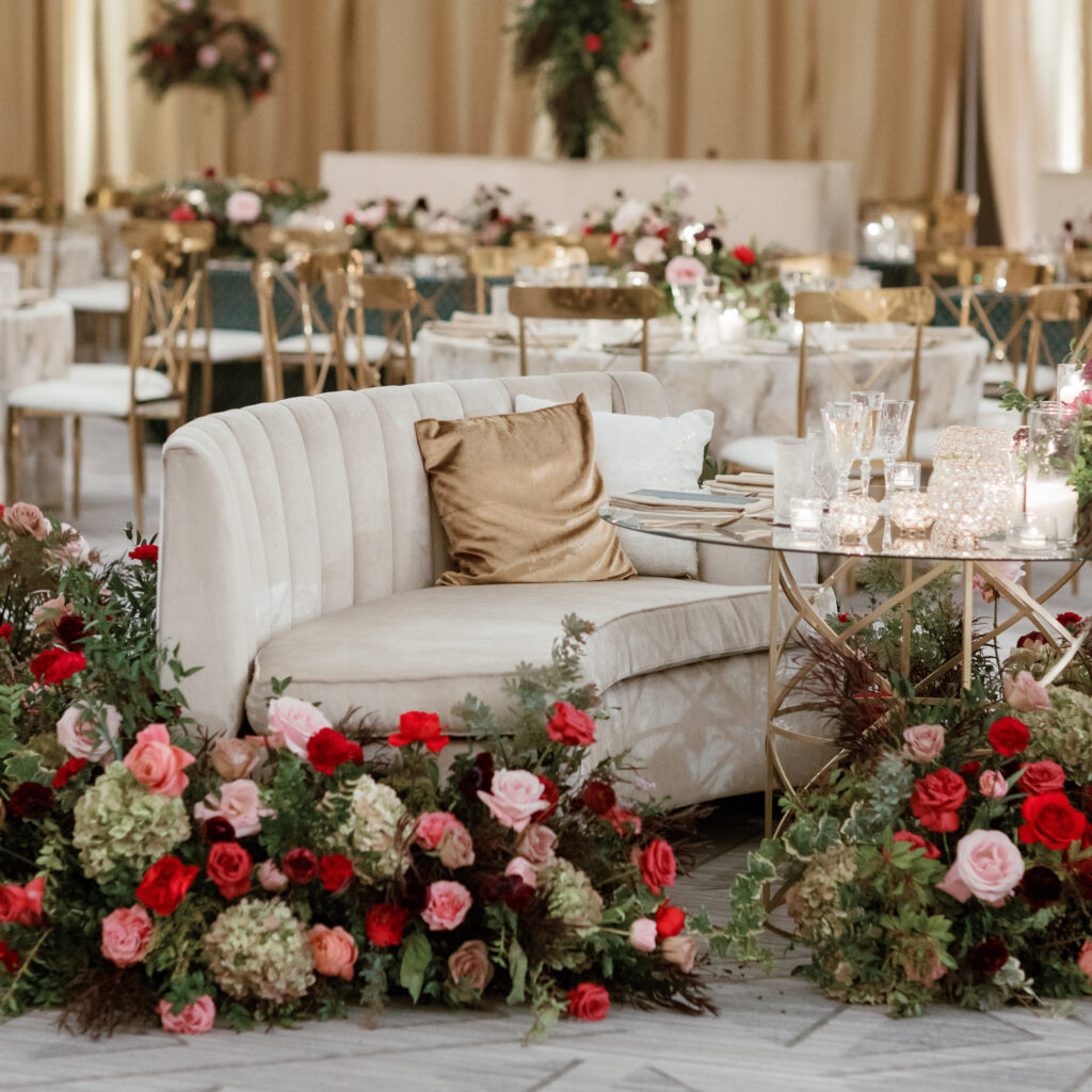 Sweetheart table surrounded by floral meadows in wedding reception. Moody jewel tone wedding reception florals in ruby, blush, plum, and magenta. Winter wedding reception at the Four Seasons. Lush floral moment for wedding sweetheart table. Design by Rosemary & Finch Floral Design. 