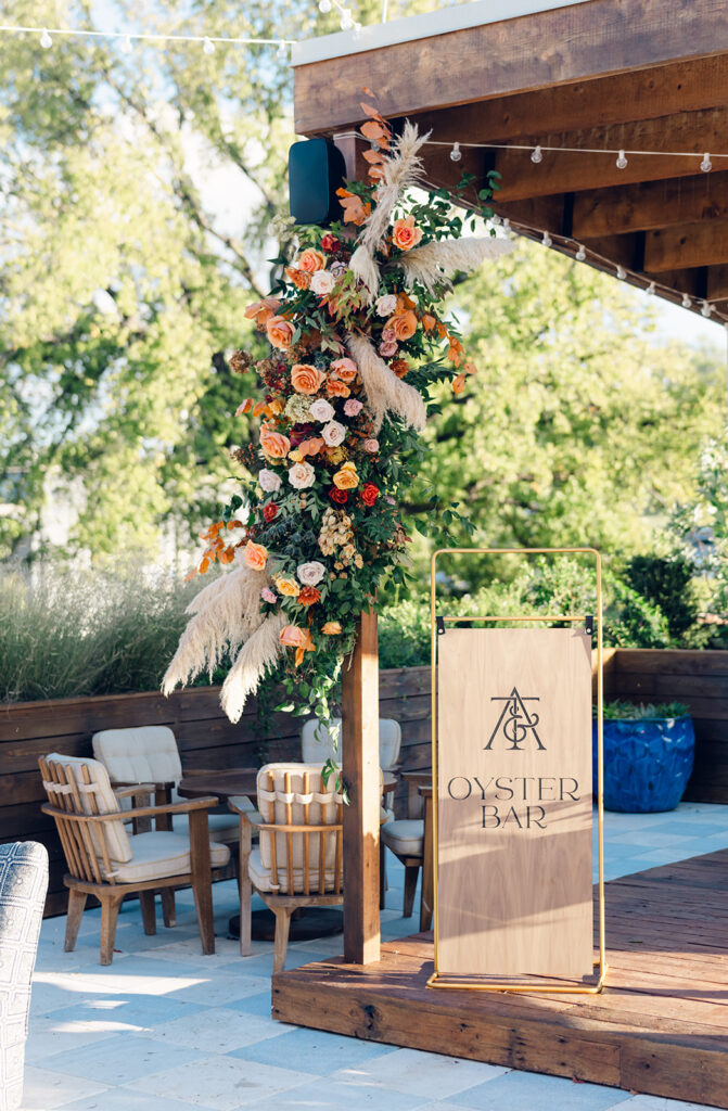 Oyster bar with floral accent installations for wedding party. Boho themed wedding welcome party with fall florals, pampas grass, and fall foliage. Fall event décor with fall foliage and florals in cream, copper, rust, and natural greens. Design by Rosemary & Finch Floral & Finch. 