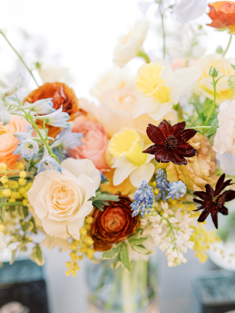 This bridal bouquet features a stunning mix of flowers in a pastel color palette, creating an elegant and romantic look. The combination of soft pastels with darker accents provides a beautiful contrast, while the mix of shapes and textures adds visual interest and depth. Bridesmaids’ bouquets accenting bridal bouquet. Winter wedding in downtown Nashville. Design by Rosemary & Finch Floral Design. 