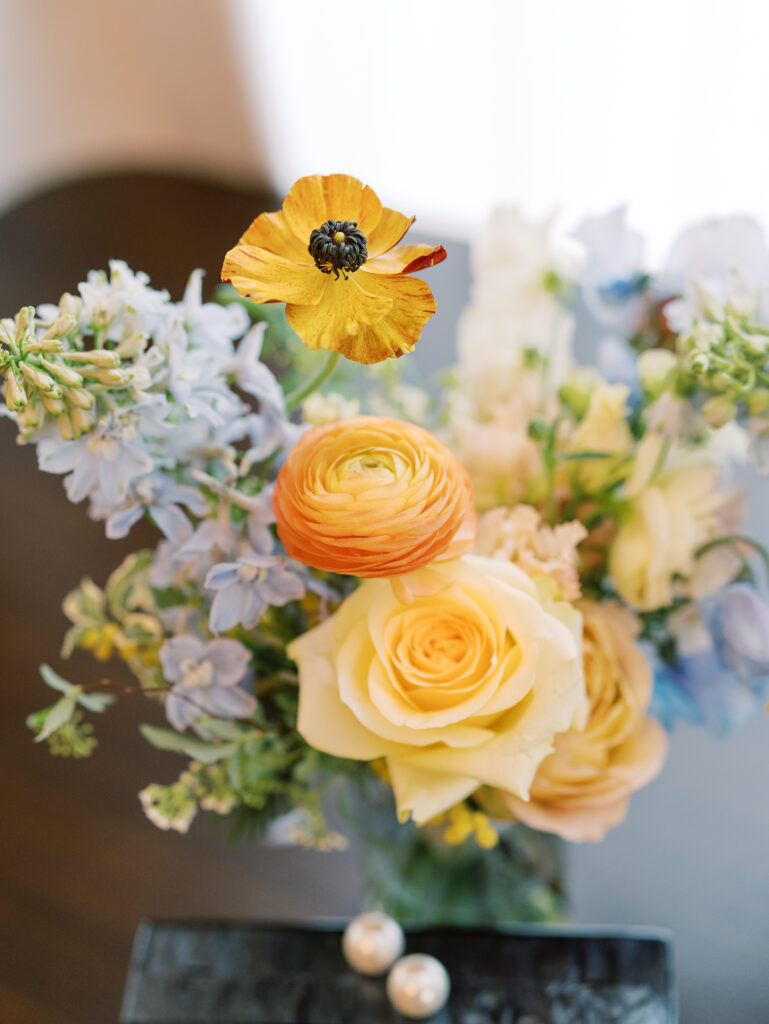 This bridal bouquet features a stunning mix of flowers in a pastel color palette, creating an elegant and romantic look. The combination of soft pastels with darker accents provides a beautiful contrast, while the mix of shapes and textures adds visual interest and depth. Bridesmaids’ bouquets accenting bridal bouquet. Winter wedding in downtown Nashville. Design by Rosemary & Finch Floral Design. 