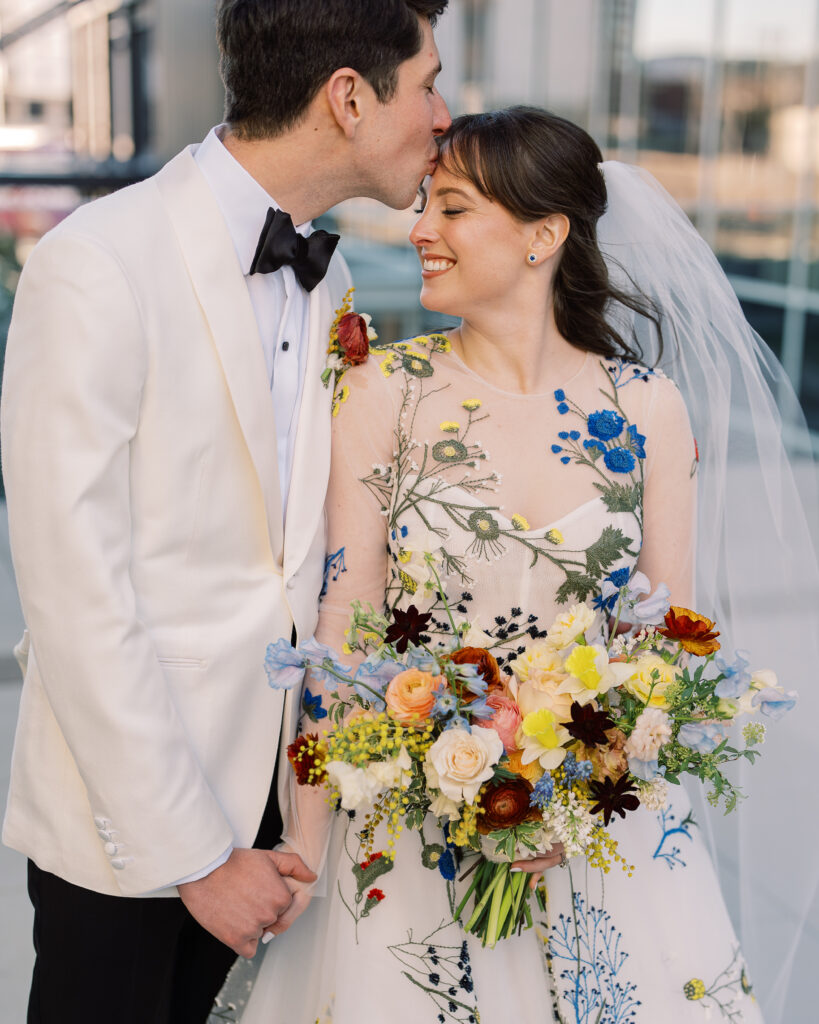 This bridal bouquet features a stunning mix of flowers in a pastel color palette, creating an elegant and romantic look. The combination of soft pastels with darker accents provides a beautiful contrast, while the mix of shapes and textures adds visual interest and depth. Bridesmaids’ bouquets accenting bridal bouquet. Winter wedding in downtown Nashville. Design by Rosemary & Finch Floral Design. 