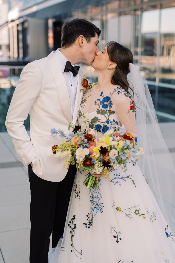 This bridal bouquet features a stunning mix of flowers in a pastel color palette, creating an elegant and romantic look. The combination of soft pastels with darker accents provides a beautiful contrast, while the mix of shapes and textures adds visual interest and depth. Bridesmaids’ bouquets accenting bridal bouquet. Winter wedding in downtown Nashville. Design by Rosemary & Finch Floral Design. 