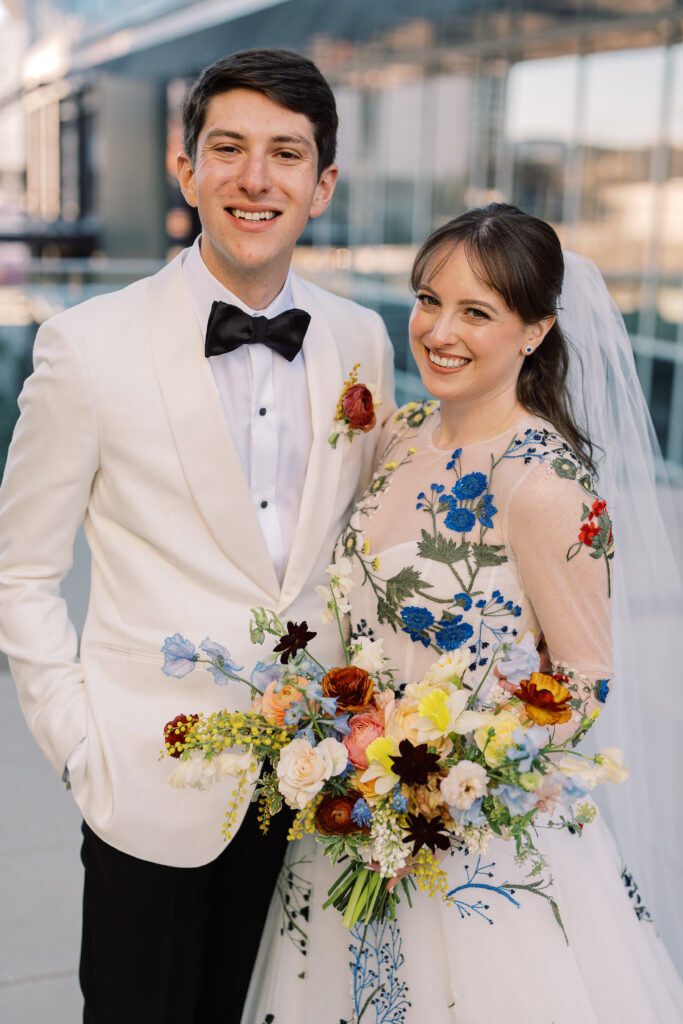 This bridal bouquet features a stunning mix of flowers in a pastel color palette, creating an elegant and romantic look. The combination of soft pastels with darker accents provides a beautiful contrast, while the mix of shapes and textures adds visual interest and depth. Bridesmaids’ bouquets accenting bridal bouquet. Winter wedding in downtown Nashville. Design by Rosemary & Finch Floral Design. 