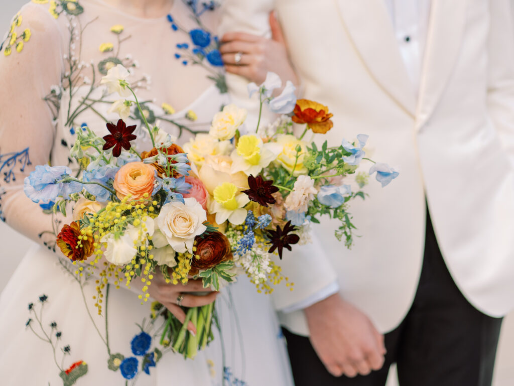 This bridal bouquet features a stunning mix of flowers in a pastel color palette, creating an elegant and romantic look. The combination of soft pastels with darker accents provides a beautiful contrast, while the mix of shapes and textures adds visual interest and depth. Bridesmaids’ bouquets accenting bridal bouquet. Winter wedding in downtown Nashville. Design by Rosemary & Finch Floral Design. 