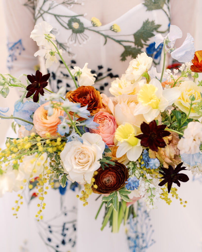 This bridal bouquet features a stunning mix of flowers in a pastel color palette, creating an elegant and romantic look. The combination of soft pastels with darker accents provides a beautiful contrast, while the mix of shapes and textures adds visual interest and depth. Bridesmaids’ bouquets accenting bridal bouquet. Winter wedding in downtown Nashville. Design by Rosemary & Finch Floral Design. 