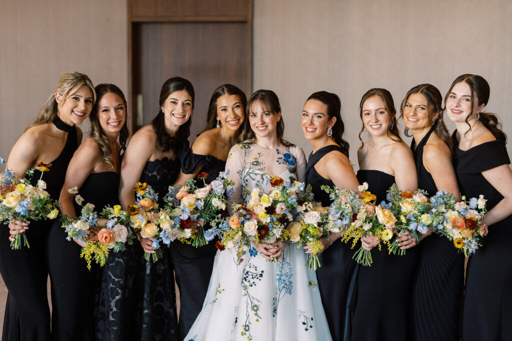 This bridal bouquet features a stunning mix of flowers in a pastel color palette, creating an elegant and romantic look. The combination of soft pastels with darker accents provides a beautiful contrast, while the mix of shapes and textures adds visual interest and depth. Bridesmaids’ bouquets accenting bridal bouquet. Winter wedding in downtown Nashville. Design by Rosemary & Finch Floral Design. 