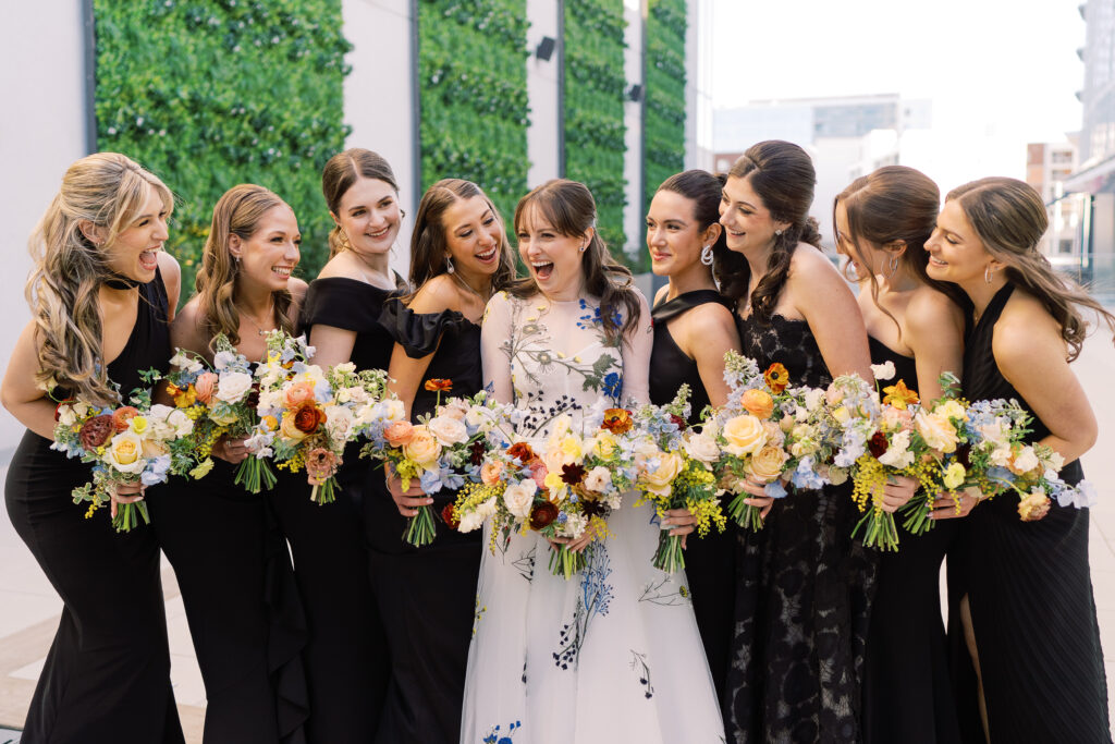 This bridal bouquet features a stunning mix of flowers in a pastel color palette, creating an elegant and romantic look. The combination of soft pastels with darker accents provides a beautiful contrast, while the mix of shapes and textures adds visual interest and depth. Bridesmaids’ bouquets accenting bridal bouquet. Winter wedding in downtown Nashville. Design by Rosemary & Finch Floral Design. 