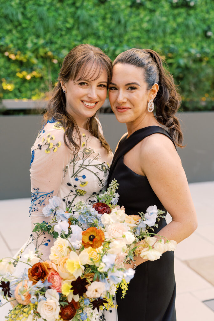 This bridal bouquet features a stunning mix of flowers in a pastel color palette, creating an elegant and romantic look. The combination of soft pastels with darker accents provides a beautiful contrast, while the mix of shapes and textures adds visual interest and depth. Bridesmaids’ bouquets accenting bridal bouquet. Winter wedding in downtown Nashville. Design by Rosemary & Finch Floral Design. 