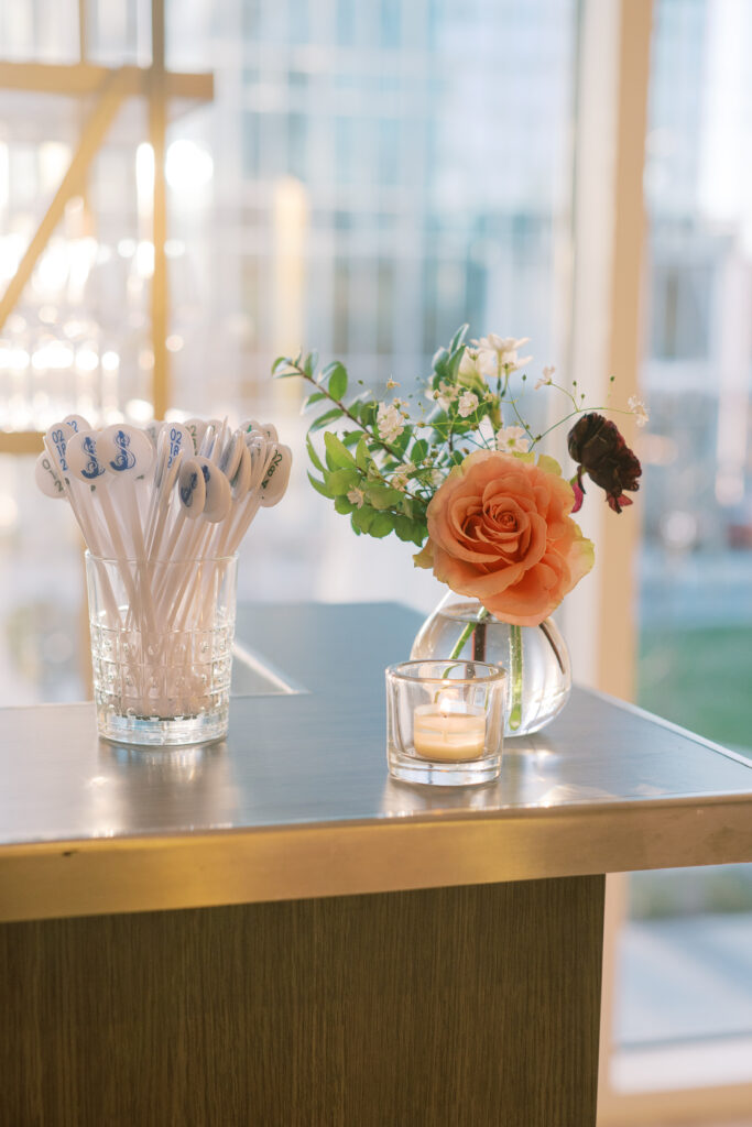 Elegant cocktail hour floral arrangements in clear glass vases. Flowers consisting of soft and vibrant hues, including shades of pink, peach, yellow, cream, and touches of burgundy, adding depth and interest. Winter wedding in downtown Nashville. Design by Rosemary & Finch Floral Design.