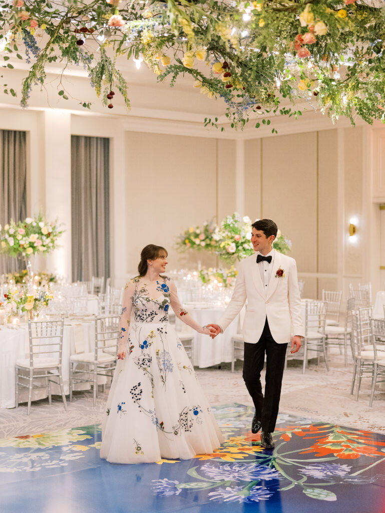 Airy garden-inspired floral installation hanging over wedding reception dance floor. Vining floral garden inspired installation gives interest to the dance floor of this winter wedding in downtown Nashville. Mixed flowers in soft pastel colors, including yellows, whites, and some darker tones like red and burgundy. Design by Rosemary & Finch Floral Design in Nashville, TN.