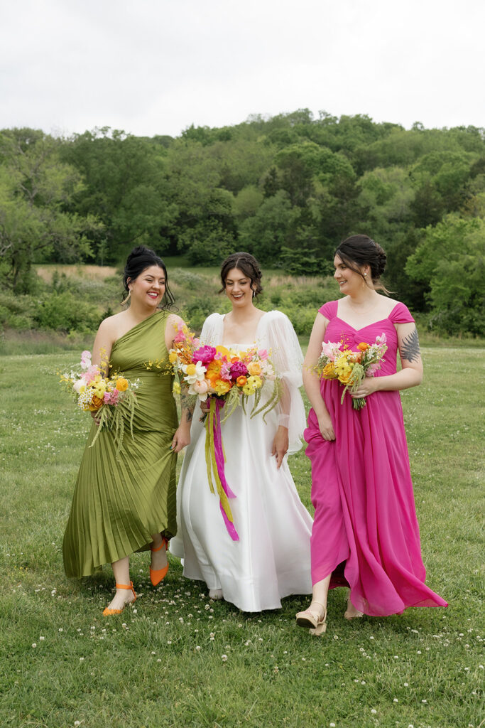 Vibrant and colorful bridal bouquet with flowers that includes lush, fully bloomed peonies in rich magenta, complemented by bright orange and yellow poppies. Summer bridal and bridesmaids’ bouquet with unique and bold spring colors. Whimsical wedding floral with statement making colors. Design by Rosemary & Finch Floral Design. 