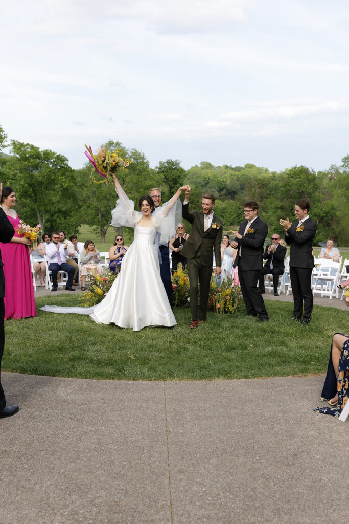 Floral ground meadows for spring wedding ceremony. Unique circle ceremony for outdoor Tennessee wedding. Ceremony floral installation includes a variety of greenery and flowers, with dominant hues of yellow and orange, accented by soft pink and white roses. Unique vibrant spring florals. Design by Rosemary & Finch Floral Design in Nashville, TN.