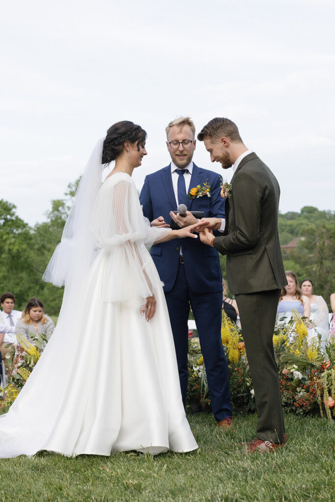 Floral ground meadows for spring wedding ceremony. Unique circle ceremony for outdoor Tennessee wedding. Ceremony floral installation includes a variety of greenery and flowers, with dominant hues of yellow and orange, accented by soft pink and white roses. Unique vibrant spring florals. Design by Rosemary & Finch Floral Design in Nashville, TN.