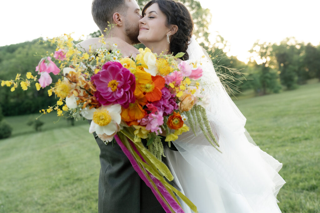 Vibrant and colorful bridal bouquet with flowers that includes lush, fully bloomed peonies in rich magenta, complemented by bright orange and yellow poppies. Summer bridal and bridesmaids’ bouquet with unique and bold spring colors. Whimsical wedding floral with statement making colors. Design by Rosemary & Finch Floral Design. 