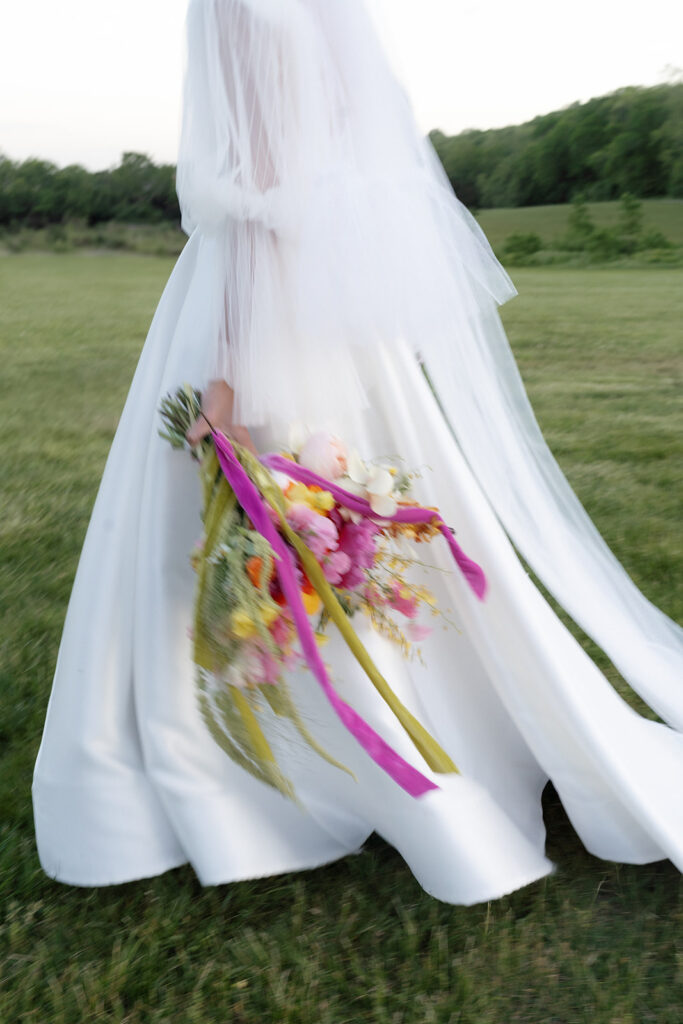 Vibrant and colorful bridal bouquet with flowers that includes lush, fully bloomed peonies in rich magenta, complemented by bright orange and yellow poppies. Summer bridal and bridesmaids’ bouquet with unique and bold spring colors. Whimsical wedding floral with statement making colors. Design by Rosemary & Finch Floral Design. 