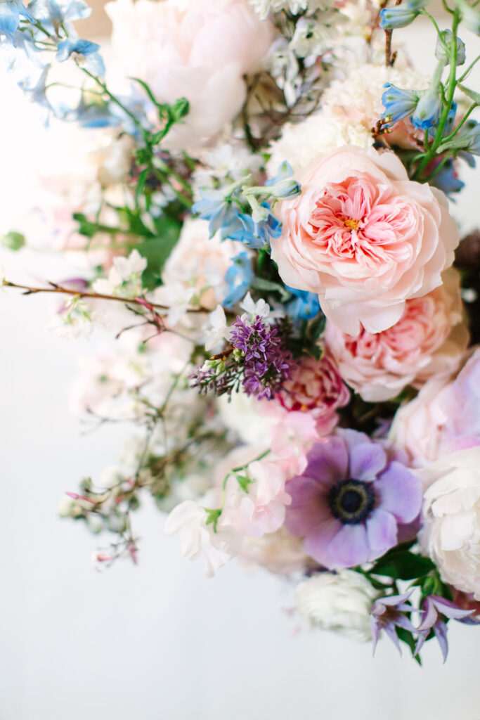 Elegant bridal bouquet in soft pastel colors, including shades of pink, white, and lavender. Mix of roses, peonies, and other delicate blooms, accented with greenery. Lush garden style bridal bouquet for spring wedding. Bridesmaids’ bouquets accenting bridal. Design by Rosemary & Finch Floral Design in Nashville, TN. 