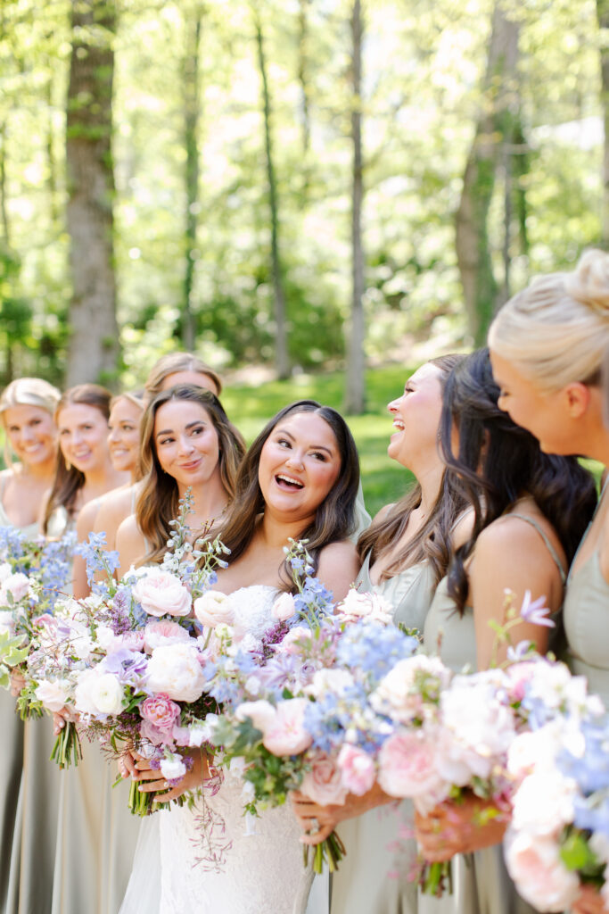 Elegant bridal bouquet in soft pastel colors, including shades of pink, white, and lavender. Mix of roses, peonies, and other delicate blooms, accented with greenery. Lush garden style bridal bouquet for spring wedding. Bridesmaids’ bouquets accenting bridal. Design by Rosemary & Finch Floral Design in Nashville, TN. 