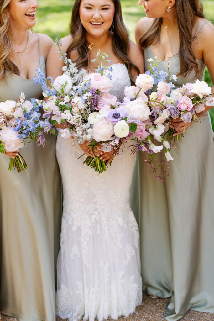 Elegant bridal bouquet in soft pastel colors, including shades of pink, white, and lavender. Mix of roses, peonies, and other delicate blooms, accented with greenery. Lush garden style bridal bouquet for spring wedding. Bridesmaids’ bouquets accenting bridal. Design by Rosemary & Finch Floral Design in Nashville, TN. 