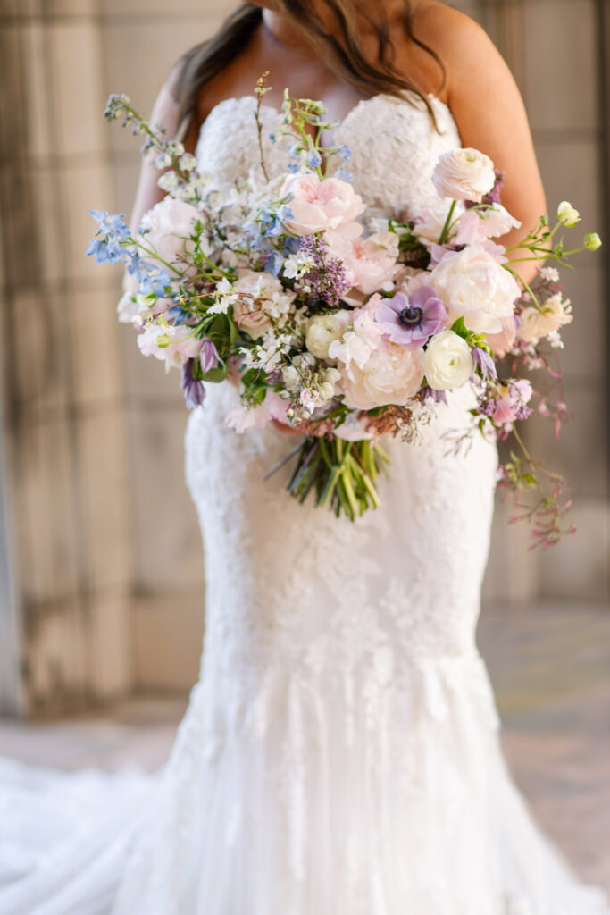 Elegant bridal bouquet in soft pastel colors, including shades of pink, white, and lavender. Mix of roses, peonies, and other delicate blooms, accented with greenery. Lush garden style bridal bouquet for spring wedding. Bridesmaids’ bouquets accenting bridal. Design by Rosemary & Finch Floral Design in Nashville, TN. 