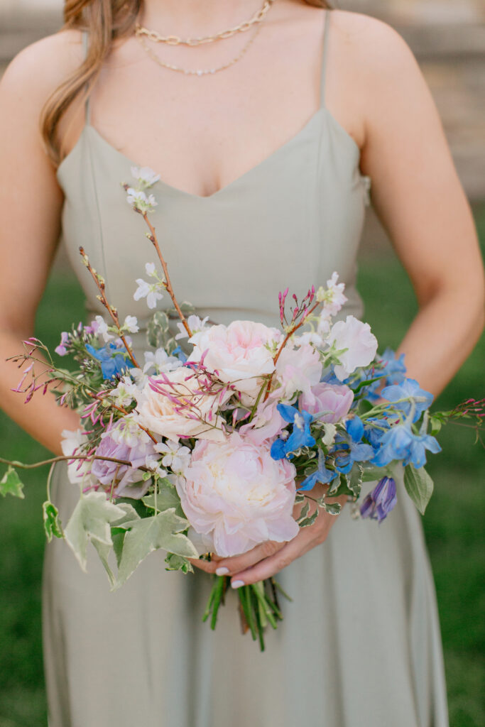 Elegant bridal bouquet in soft pastel colors, including shades of pink, white, and lavender. Mix of roses, peonies, and other delicate blooms, accented with greenery. Lush garden style bridal bouquet for spring wedding. Bridesmaids’ bouquets accenting bridal. Design by Rosemary & Finch Floral Design in Nashville, TN. 