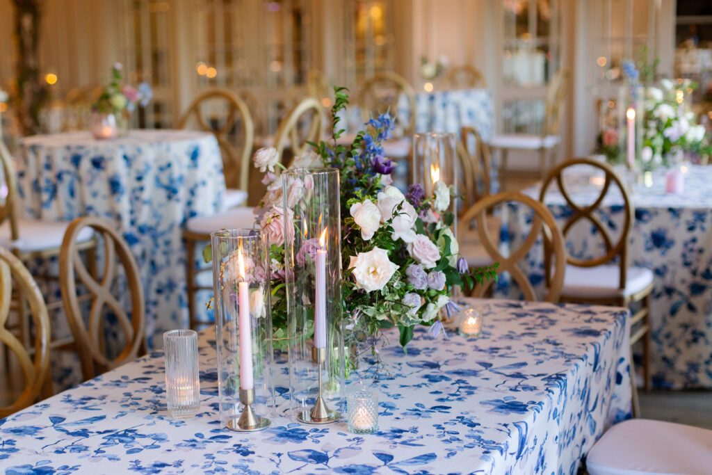 Garden-inspired centerpieces for spring wedding reception. Whimsical floral design with petal heavy florals in low compotes and bud vases. Pastel color palette for spring wedding which shades of pink, purple, lavender, and cream. Tasteful candlelight with mixed metals and pastel taper candles. Design by Rosemary & Finch Floral Design in Nashville, TN. 