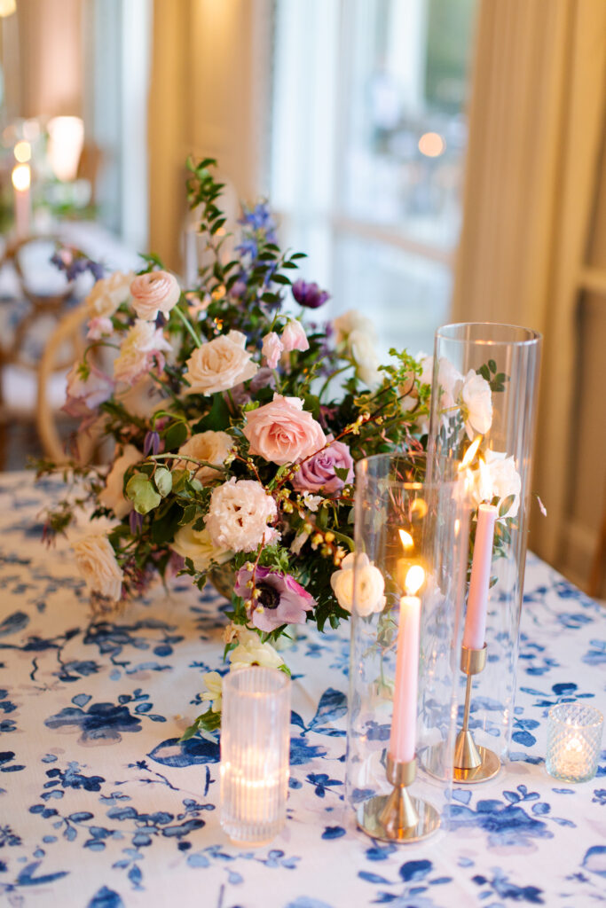 Garden-inspired centerpieces for spring wedding reception. Whimsical floral design with petal heavy florals in low compotes and bud vases. Pastel color palette for spring wedding which shades of pink, purple, lavender, and cream. Tasteful candlelight with mixed metals and pastel taper candles. Design by Rosemary & Finch Floral Design in Nashville, TN. 